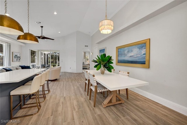 dining area featuring ceiling fan with notable chandelier, high vaulted ceiling, and light hardwood / wood-style flooring