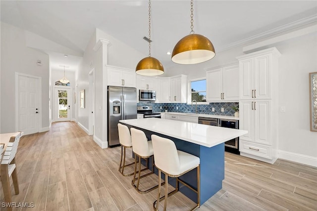 kitchen with pendant lighting, a kitchen island, white cabinetry, and stainless steel appliances