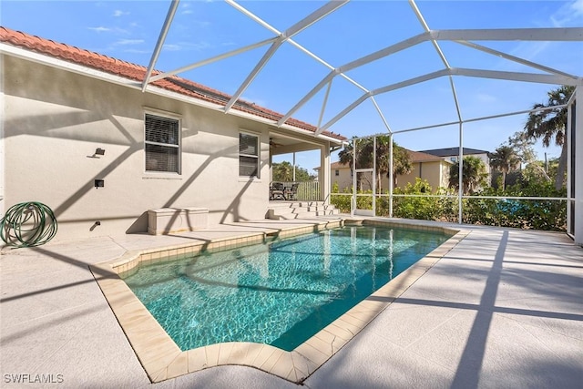 view of swimming pool featuring glass enclosure and a patio area