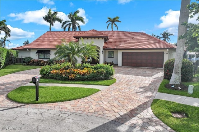 mediterranean / spanish-style house featuring a garage, decorative driveway, a tile roof, and stucco siding