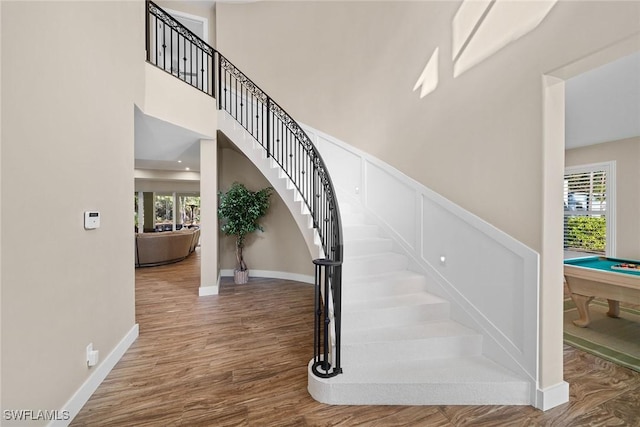 stairs featuring hardwood / wood-style floors, a high ceiling, and pool table