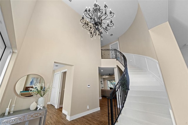 staircase with hardwood / wood-style floors, a high ceiling, and an inviting chandelier