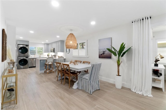 dining room featuring stacked washer and dryer, baseboards, light wood finished floors, and recessed lighting