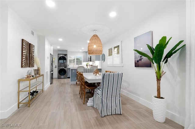 dining room featuring stacked washer and dryer and light hardwood / wood-style flooring