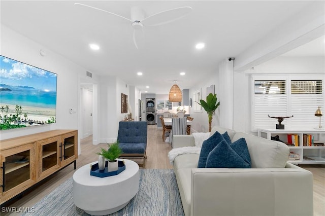 living room featuring stacked washer / drying machine, visible vents, light wood finished floors, and recessed lighting