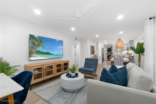 living area with light wood-style floors, stacked washer / dryer, ceiling fan, and recessed lighting