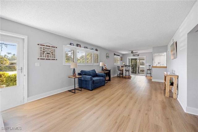 living room with a wealth of natural light, ceiling fan, light hardwood / wood-style floors, and a textured ceiling