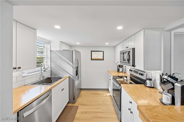 kitchen with decorative backsplash, stainless steel appliances, sink, light hardwood / wood-style flooring, and white cabinetry