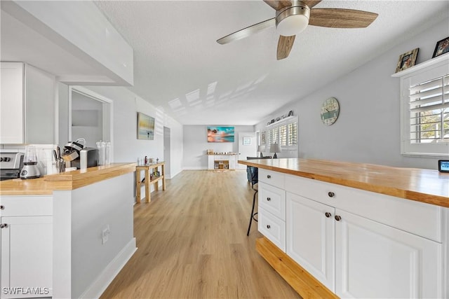 kitchen featuring butcher block counters, ceiling fan, white cabinets, and light hardwood / wood-style floors