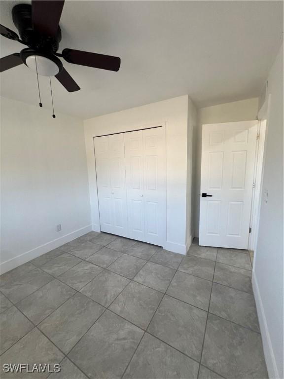 unfurnished bedroom with ceiling fan, light tile patterned floors, and a closet