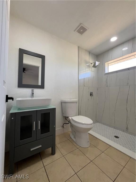 bathroom with tiled shower, vanity, toilet, and tile patterned flooring