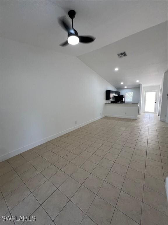 unfurnished living room featuring ceiling fan, light tile patterned floors, and vaulted ceiling