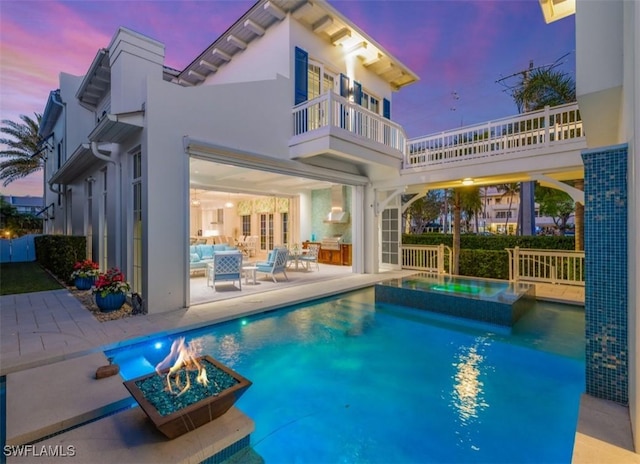 pool at dusk with a patio area and an in ground hot tub