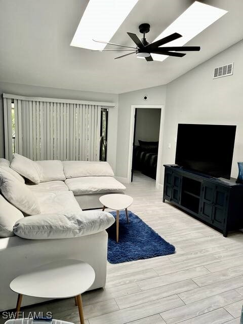 living room featuring ceiling fan, light hardwood / wood-style floors, and lofted ceiling