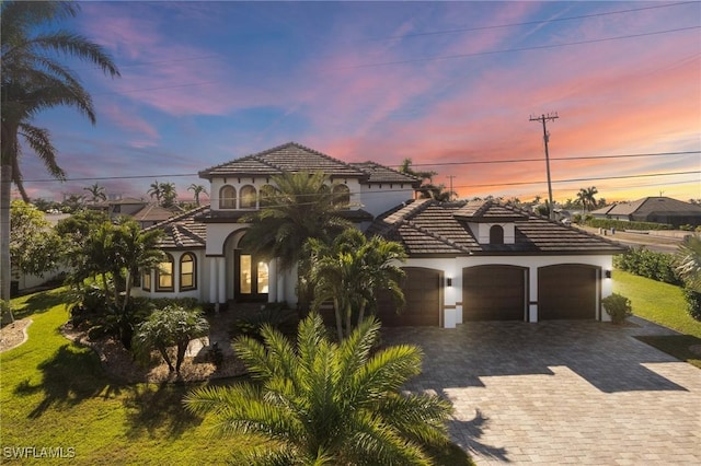 mediterranean / spanish house with a garage and a lawn