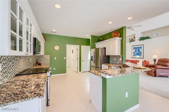 kitchen featuring kitchen peninsula, sink, light stone countertops, appliances with stainless steel finishes, and white cabinetry