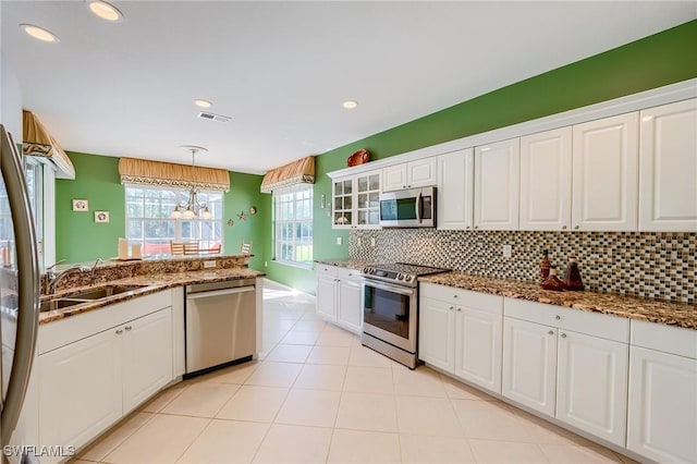 kitchen with pendant lighting, white cabinets, sink, appliances with stainless steel finishes, and tasteful backsplash