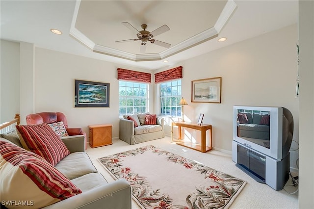 carpeted living room featuring a raised ceiling, ceiling fan, and ornamental molding