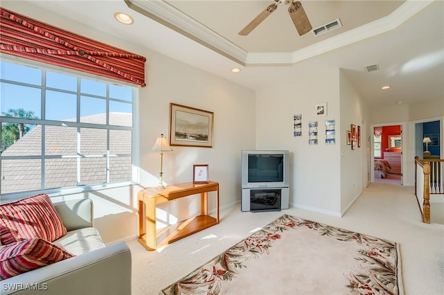 living room featuring carpet floors, a tray ceiling, ceiling fan, and ornamental molding