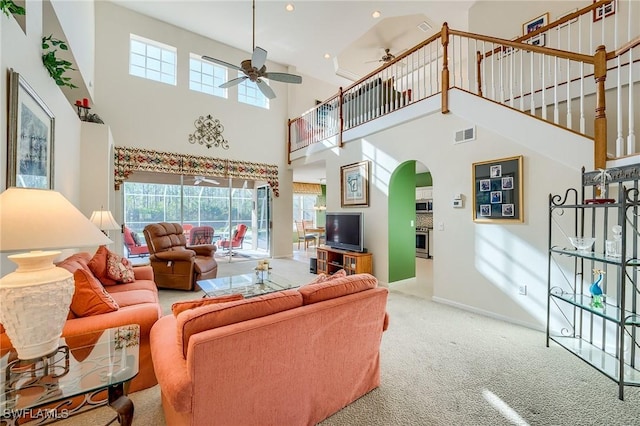 living room featuring carpet flooring, a towering ceiling, and ceiling fan