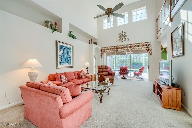 carpeted living room with ceiling fan and a towering ceiling