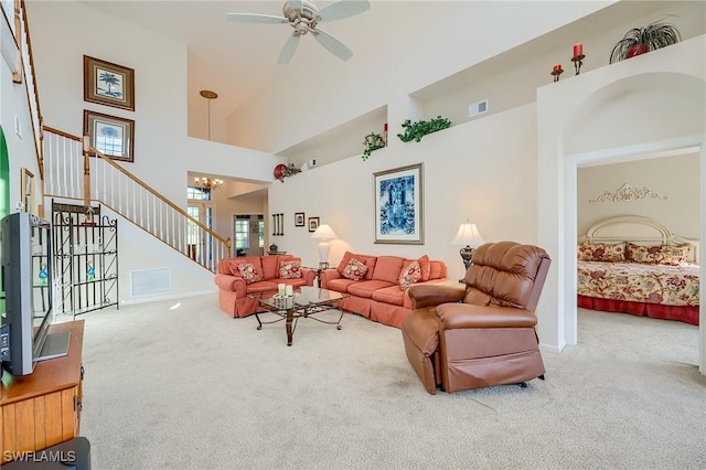 carpeted living room with a high ceiling and ceiling fan with notable chandelier