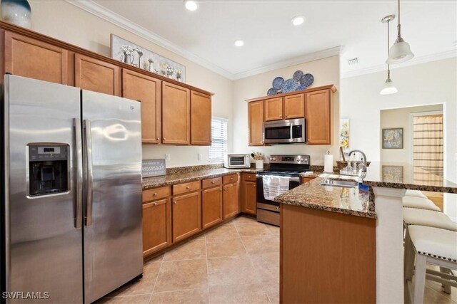20680 Vita Ct, Venice, FL 34293 - kitchen with stainless steel appliances, a peninsula, brown cabinets, a kitchen breakfast bar, and ornamental molding