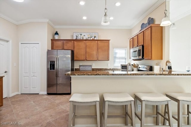 20680 Vita Ct, Venice, FL 34293 - kitchen with stainless steel appliances, brown cabinetry, dark stone counters, crown molding, and recessed lighting