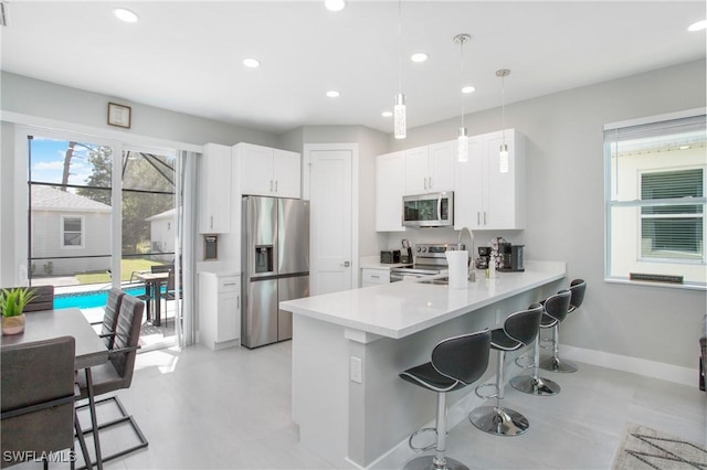 kitchen with pendant lighting, a kitchen breakfast bar, kitchen peninsula, and appliances with stainless steel finishes