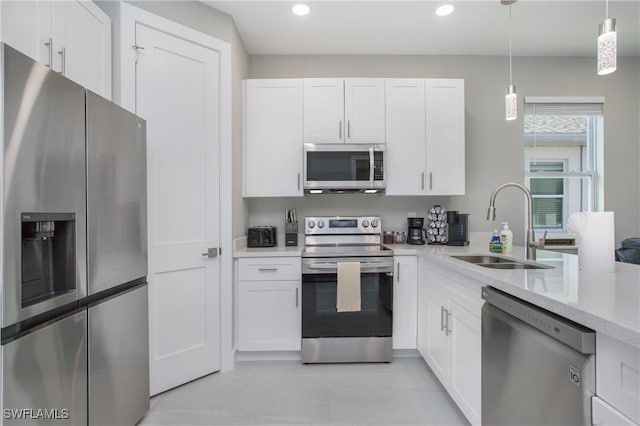 kitchen with decorative light fixtures, sink, white cabinetry, and stainless steel appliances