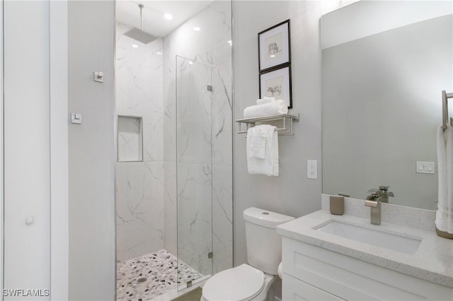 bathroom with tiled shower, vanity, and toilet