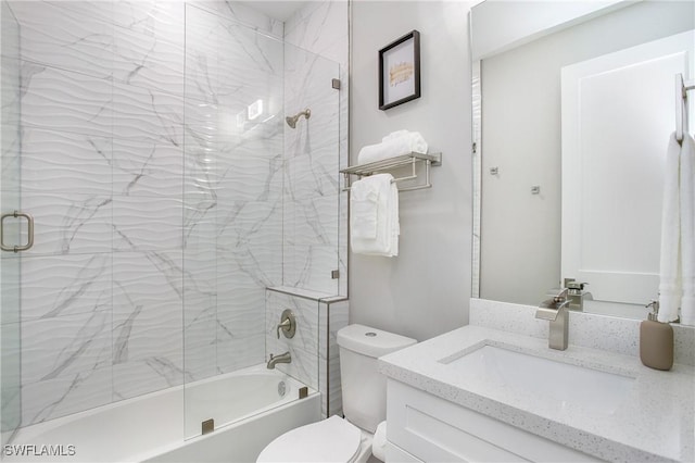 full bathroom featuring vanity, combined bath / shower with glass door, and toilet