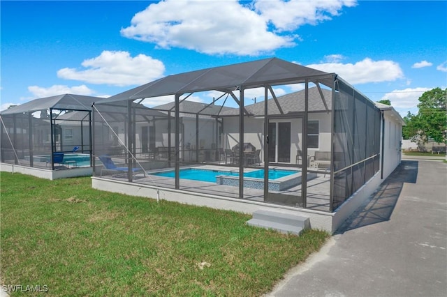 view of pool featuring glass enclosure, a yard, and a patio