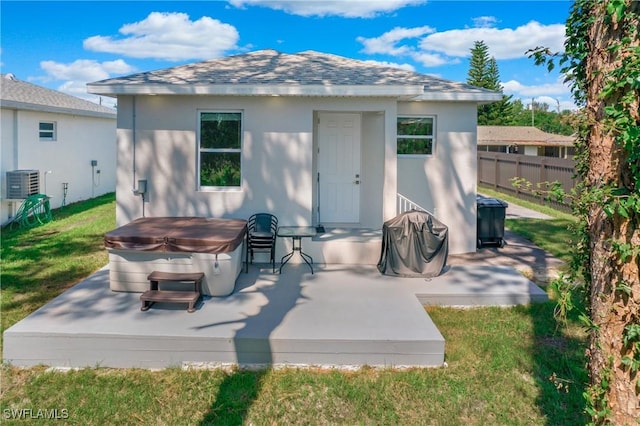 rear view of property with a yard, central AC, a hot tub, and a wooden deck