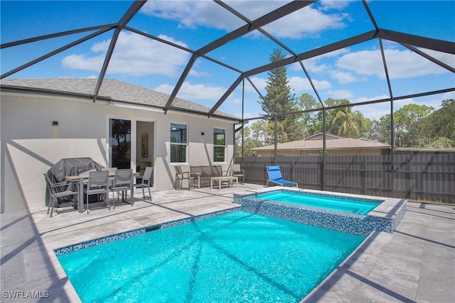 view of pool featuring glass enclosure, an in ground hot tub, and a patio