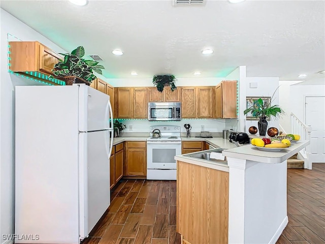 kitchen featuring dark hardwood / wood-style floors, sink, white appliances, and kitchen peninsula