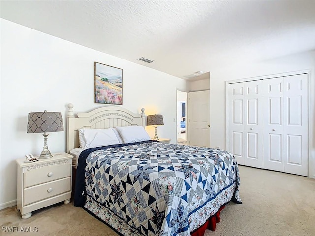 bedroom with light carpet, a textured ceiling, and a closet