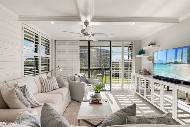 living room with beamed ceiling, ceiling fan, a healthy amount of sunlight, and ornamental molding