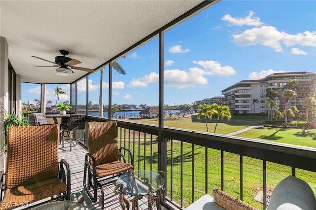 sunroom with ceiling fan and a water view