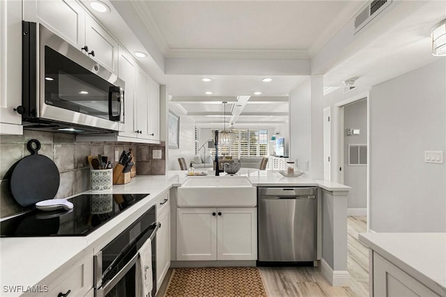 kitchen with light wood-type flooring, white cabinetry, kitchen peninsula, and appliances with stainless steel finishes