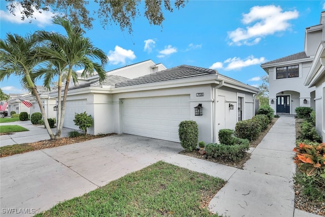 view of side of property featuring an attached garage, a tile roof, concrete driveway, and stucco siding