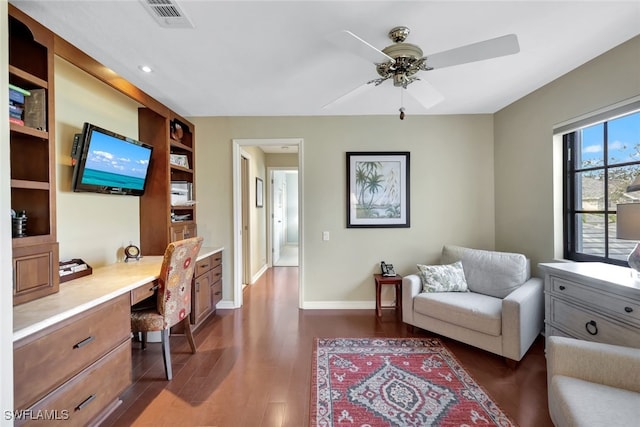 office with dark hardwood / wood-style floors, ceiling fan, and built in desk