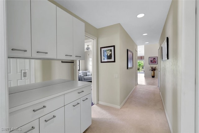 hallway with baseboards, recessed lighting, and light colored carpet