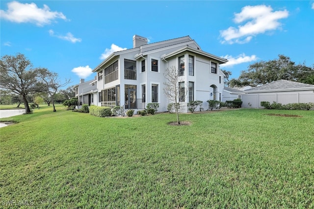 back of house featuring a sunroom and a lawn