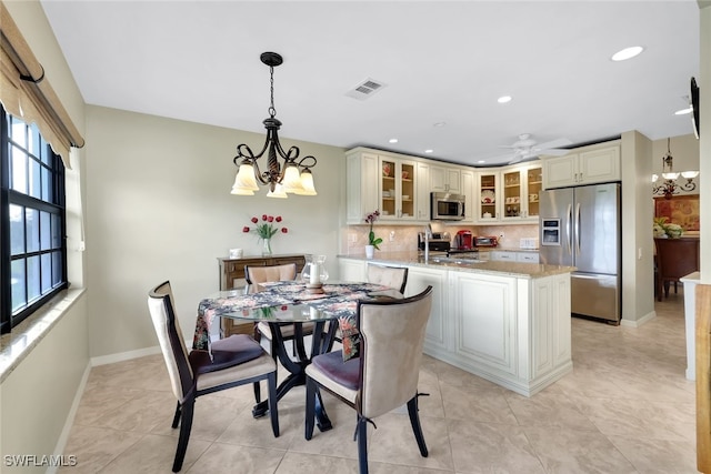 tiled dining room featuring ceiling fan with notable chandelier