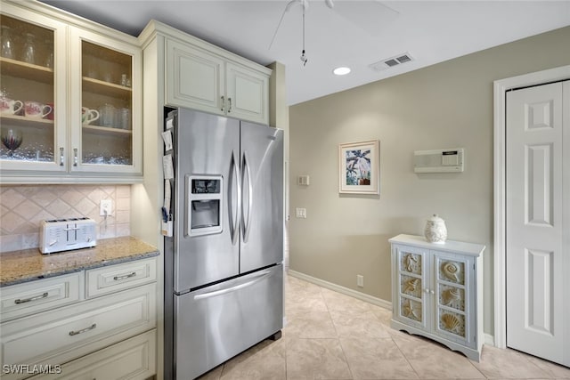 kitchen with light stone counters, light tile patterned floors, tasteful backsplash, and stainless steel fridge