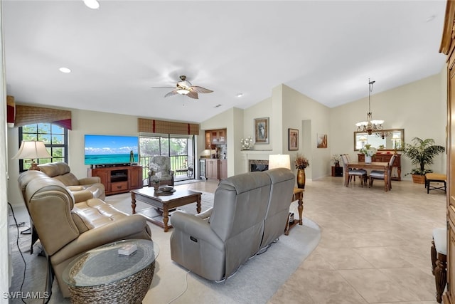 living room with ceiling fan with notable chandelier, a healthy amount of sunlight, light tile patterned floors, and lofted ceiling