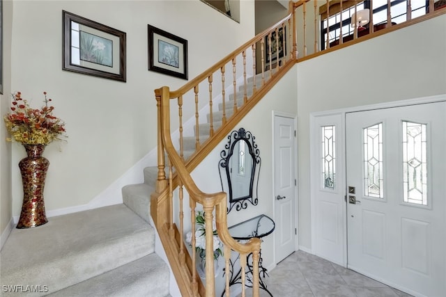 foyer entrance featuring stairs, plenty of natural light, a high ceiling, and light tile patterned floors