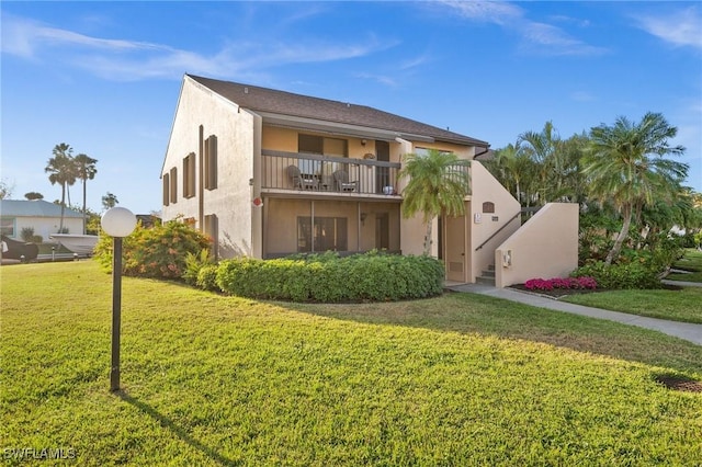 view of front of house featuring a balcony and a front lawn