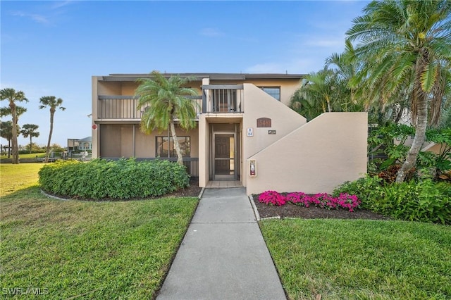 view of front of house featuring a front yard and a balcony